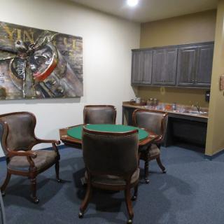 A small meeting room with a round table, four chairs, and artwork on the wall.