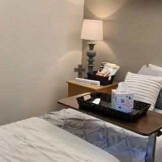 A cozy bedroom featuring a neatly made bed with pillows, a side table with a lamp, and decorative items.