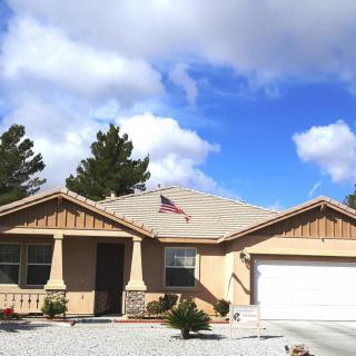 A suburban house with a garage, set against a bright blue sky with scattered clouds.