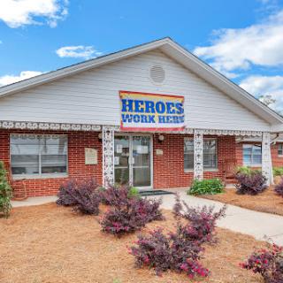 A welcoming building with a sign indicating 'Heroes Work Here', surrounded by well-maintained landscaping.