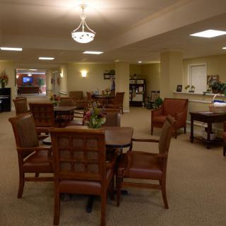 A cozy dining area with multiple tables and chairs, softly illuminated by ceiling lights.