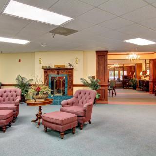 A traditional lobby interior with pink upholstered chairs and a fireplace.