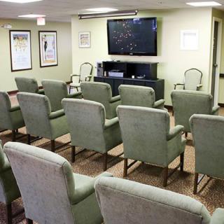 A conference room with arranged seating facing a large television screen.