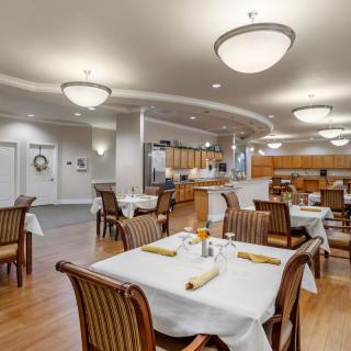 A modern dining room with elegantly arranged tables and chairs under soft lighting.