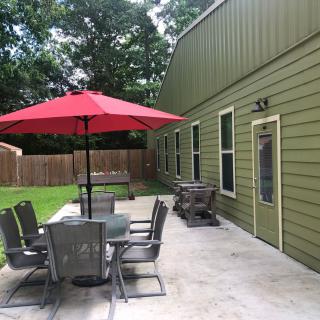 A backyard patio with a table, chairs, and a red umbrella beside a house.