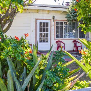 A cozy house with a vibrant garden and patio chairs.