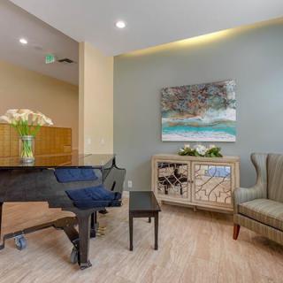 A modern living room featuring a grand piano, comfortable seating, and elegant decor.