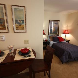 A cozy bedroom with an adjacent dining area, featuring a neatly set table and warm lighting.