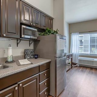 Modern apartment kitchen with stainless steel appliances and wooden cabinetry.