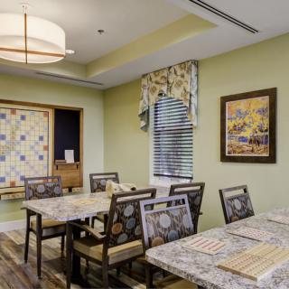 A modern dining room with patterned chairs and a quilt on the wall, featuring elegant interior design and artwork.