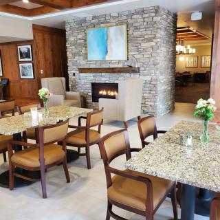 A cozy dining area with granite tables, wooden chairs, a stone fireplace, and elegant decor.