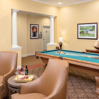 A cozy game room featuring a pool table and leather seating, accented by wall art and a warm color scheme.