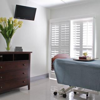 A minimalist room with a bed, dresser, and television.