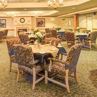 An elegant dining room with neatly arranged tables and chairs, featuring floral centerpieces.