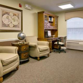 A cozy office space with comfortable armchairs, a wooden bookshelf, and a decorative globe.