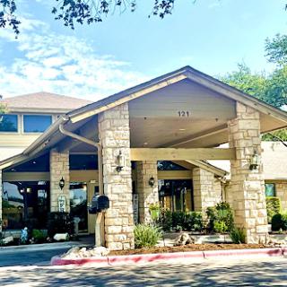 The inviting entrance of a hotel, featuring beautiful stonework and well-maintained landscaping.