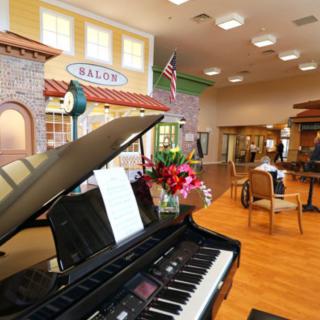 A cozy community center with a piano and a caf-style seating area.