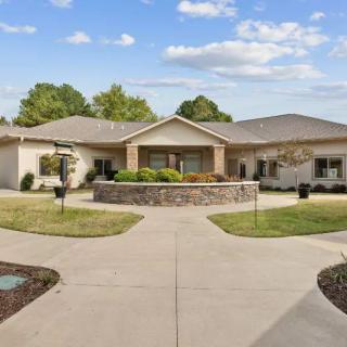 A single-story residential building with a landscaped front yard and circular driveway.