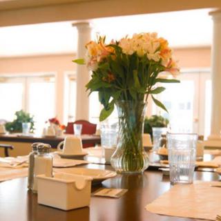 A beautifully set dining table with a vase of flowers in a well-lit restaurant.