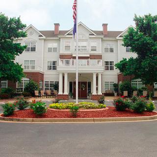 A hotel with a landscaped entrance and flagpole.