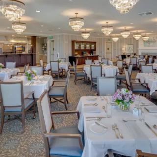 An elegant dining room with neatly arranged tables and chairs, adorned with chandeliers.