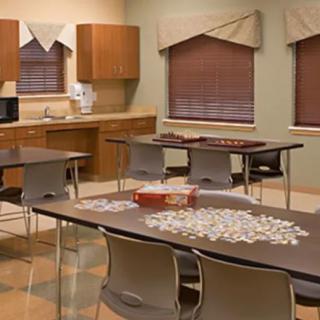 A classroom with tables, chairs, and puzzle pieces arranged for an activity.