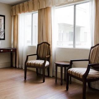 A bright room with two chairs and a desk, featuring large windows and wooden flooring.
