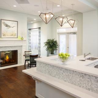 A modern kitchen with a stylish countertop, pendant lights, and a cozy fireplace.