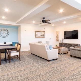 A spacious and modern living room featuring a cozy seating area, dining table, and large television.