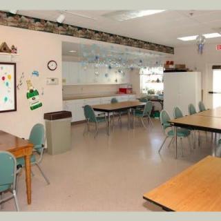 An empty classroom with tables and chairs arranged neatly, decorated walls, and bright lighting.
