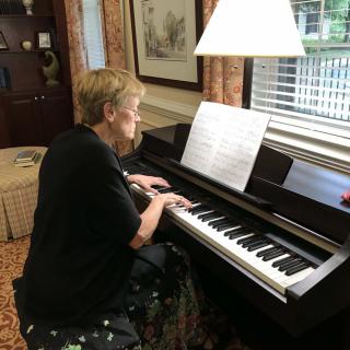 A woman playing the piano with sheet music in front of her.