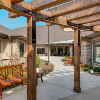 A serene courtyard with wooden pergola and outdoor seating surrounded by stone buildings.