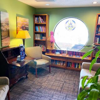 A cozy reading room with bookshelves, comfortable chairs, and a bright circular window.