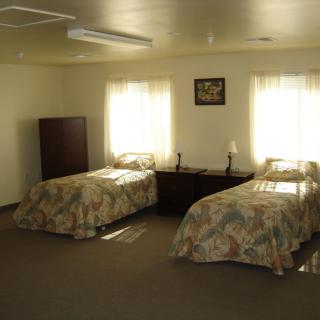 A cozy bedroom with two twin beds, a small table, and a wardrobe.