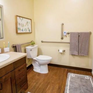 A clean and well-organized bathroom with a toilet, sink, mirror, and towels.