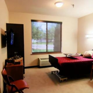 A clean and organized hospital room with a bed, television, and large window.