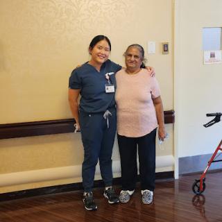 A caregiver and an elderly woman pose together, celebrating companionship and care.