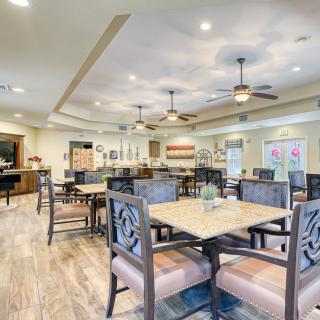 A spacious and modern dining area featuring stylish furniture, warm lighting, and ceiling fans.