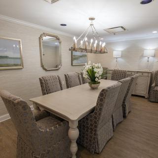 Elegant dining room with a long table, upholstered chairs, and a chandelier.