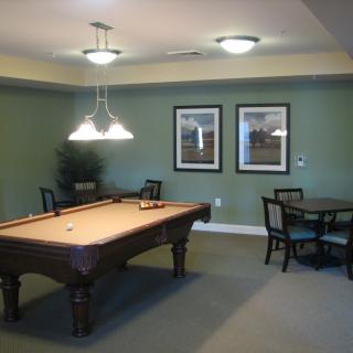 A cozy billiards room featuring a pool table, green-painted walls, and framed artwork.