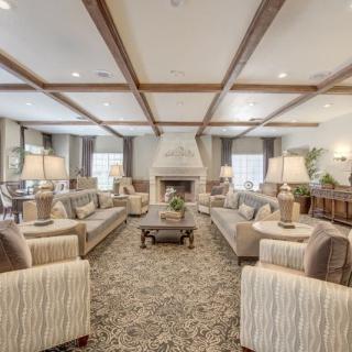 A spacious and elegantly designed living room with multiple sofas, a central fireplace, and warm lighting.