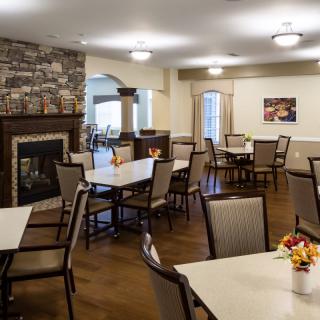 A cozy dining area with neatly arranged tables and a warm fireplace.