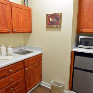 A small kitchen area with wooden cabinets, a sink, microwave, and a refrigerator.