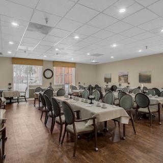 An empty dining room with neatly arranged tables and chairs, featuring warm lighting.