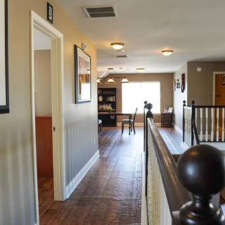 A cozy hallway in a house featuring wooden floors and natural lighting.