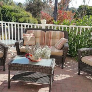 Cozy outdoor patio setup with wicker furniture and garden view.