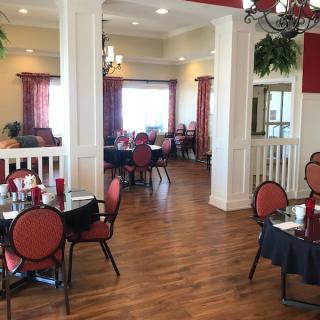 A cozy dining area with wooden floors and red-themed decor features elegant tables and chairs.