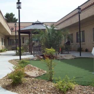 A landscaped courtyard with a pathway, garden, and outdoor seating area surrounded by buildings.