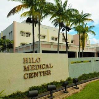 The entrance to Hilo Medical Center, surrounded by palm trees and a modern architectural design.