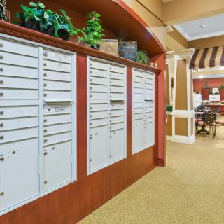 A hallway with a row of mailboxes and decorative plants overhead.